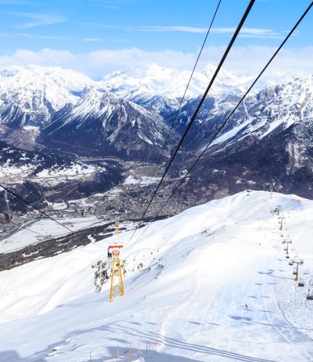 Vista alpina con neve, seggiovia e montagne.