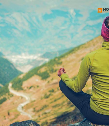 Donna medita in montagna, natura avvolgente e pace interiore.