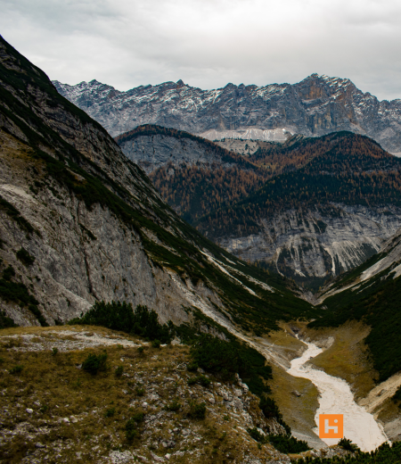 Montagne imponenti, valli profonde, natura selvaggia e cielo grigio.