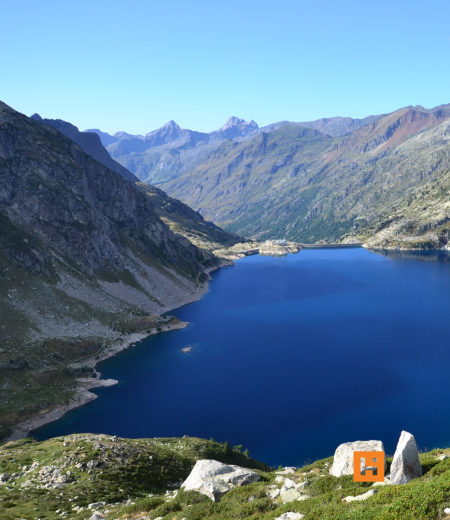 Lago alpino blu intenso tra montagne maestose e cielo limpido.