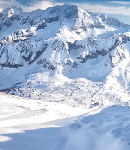 Scialpinista seduto, ammira le montagne innevate.