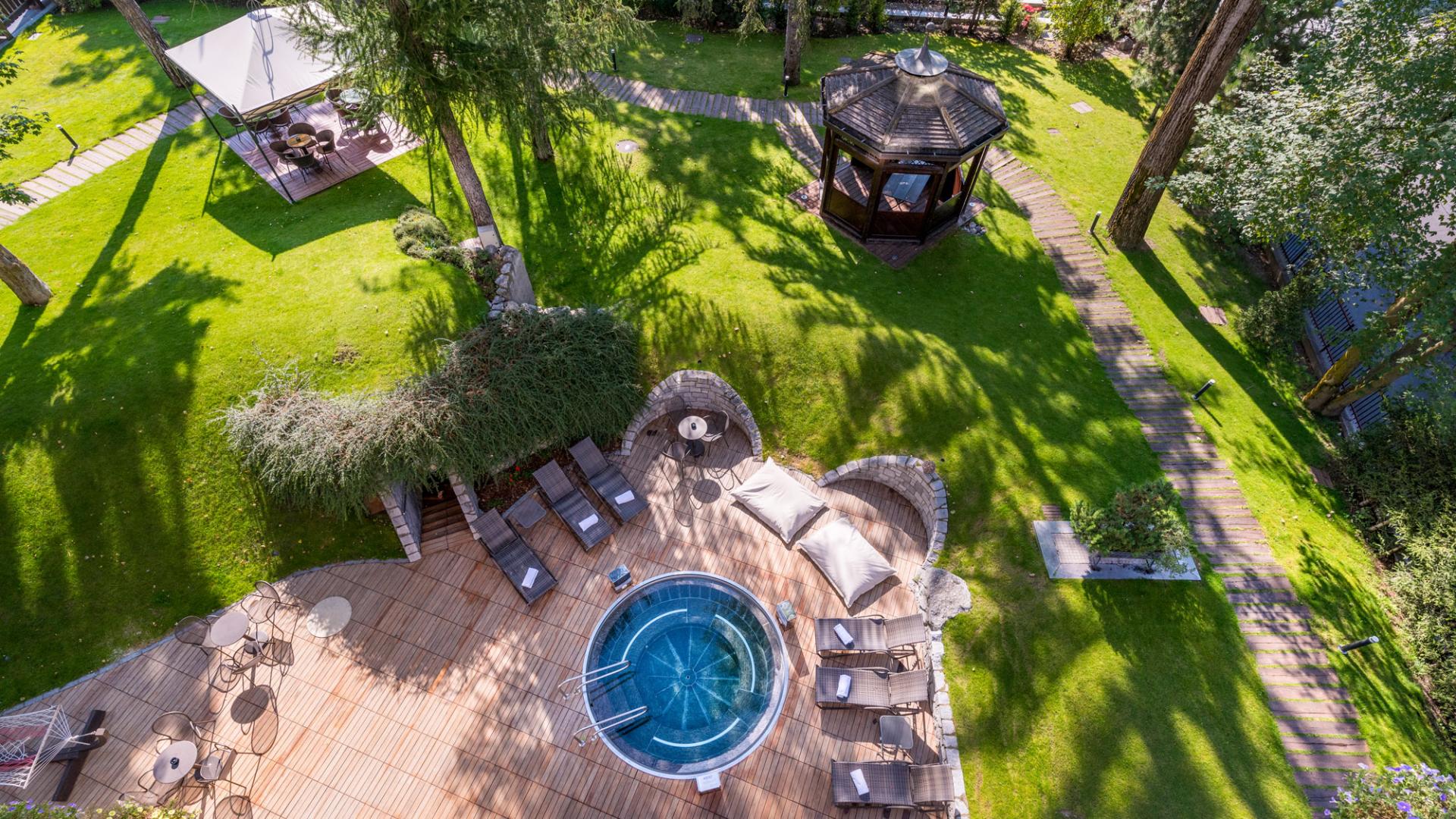 Garten mit Whirlpool und Pavillon, von Bäumen umgeben.