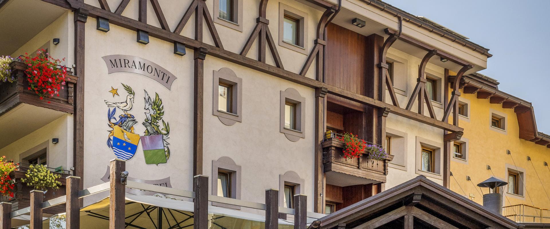 Hotel Miramonti con balconi fioriti e stemma decorativo sulla facciata.