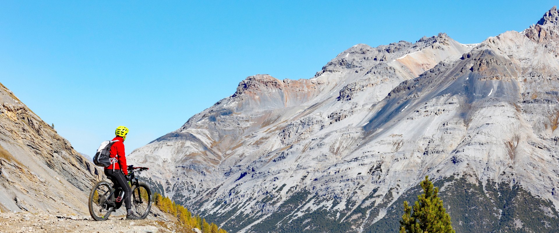 Ciclista in montagna con paesaggio roccioso e cielo azzurro.