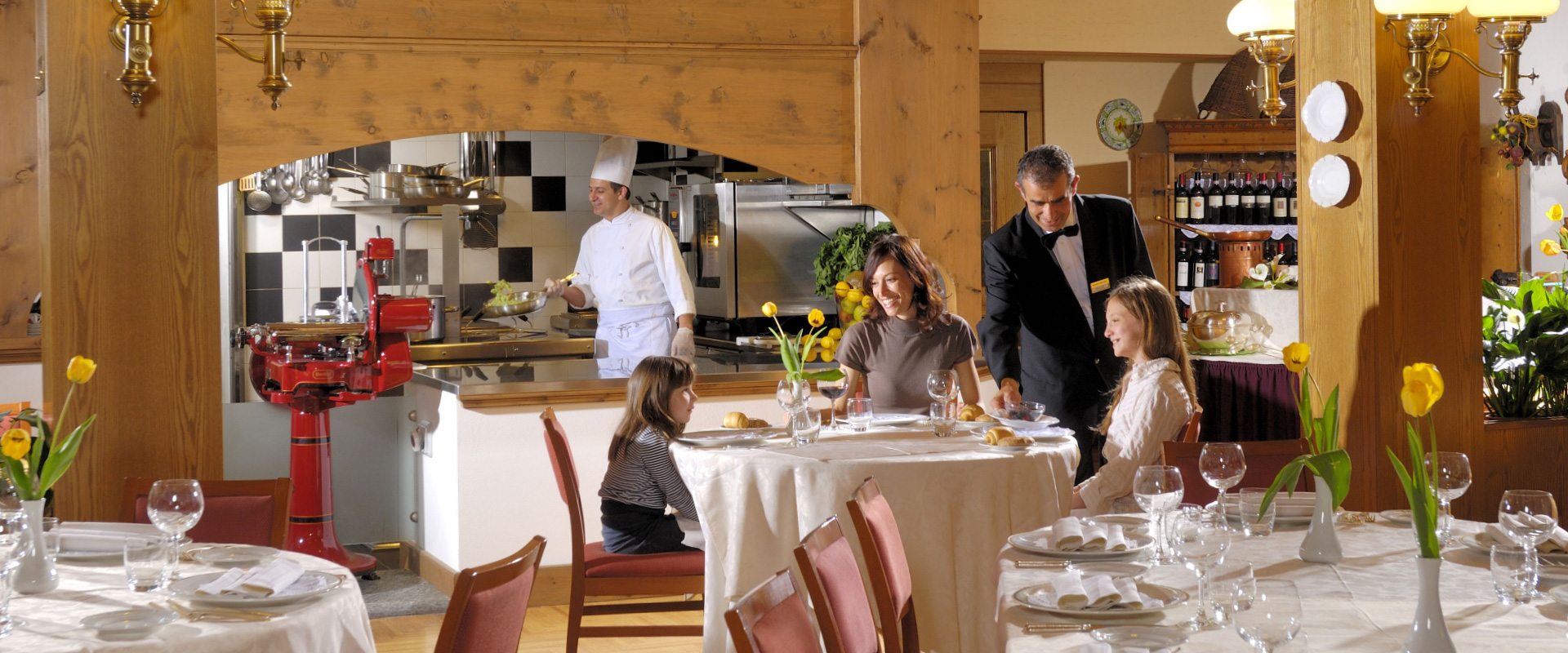 Una famiglia cena in un ristorante mentre lo chef cucina in cucina a vista.