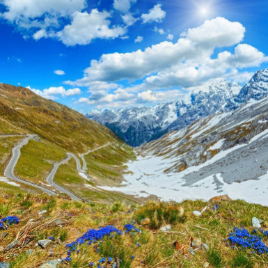 Auto sportive colorate su una strada di montagna, con un paesaggio mozzafiato.