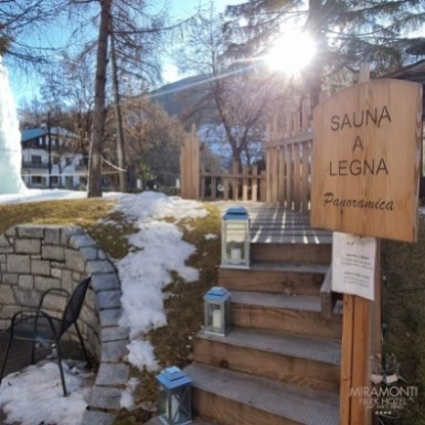 Scalinata verso sauna a legna con vista panoramica in un ambiente innevato.