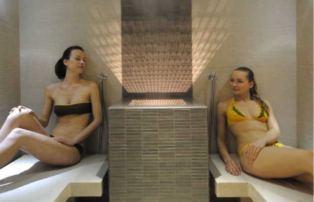 Due donne rilassate in costume da bagno all'interno di una sauna moderna.