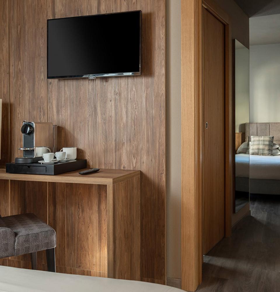 Chambre moderne avec TV, bureau et machine à café.