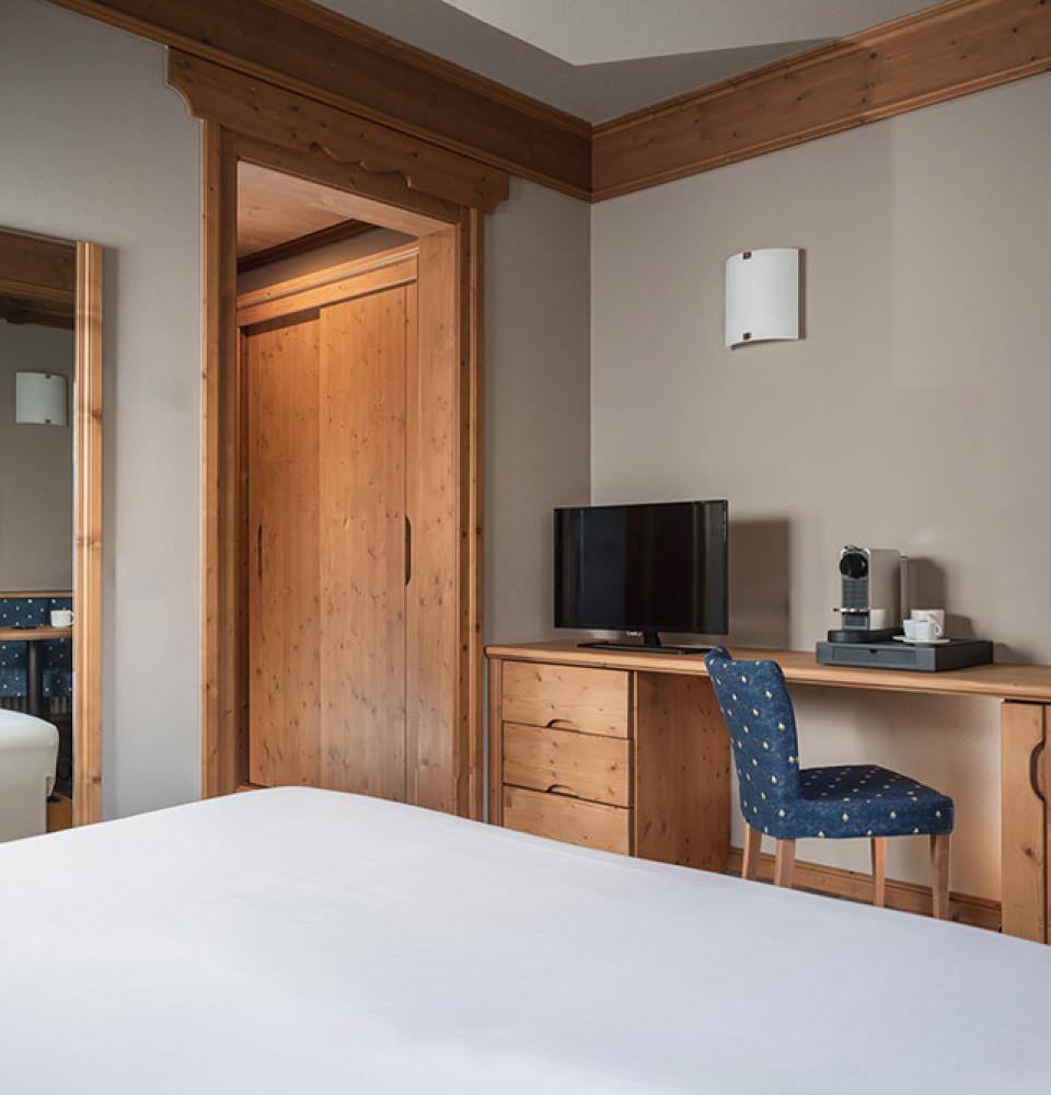 Chambre d'hôtel avec meubles en bois, TV et machine à café.