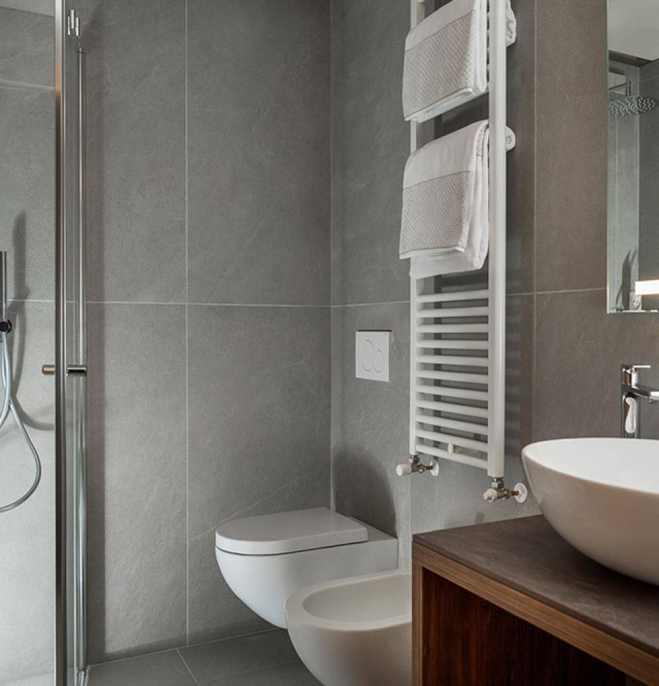 Salle de bains moderne avec douche, lavabo, WC et chauffe-serviettes.