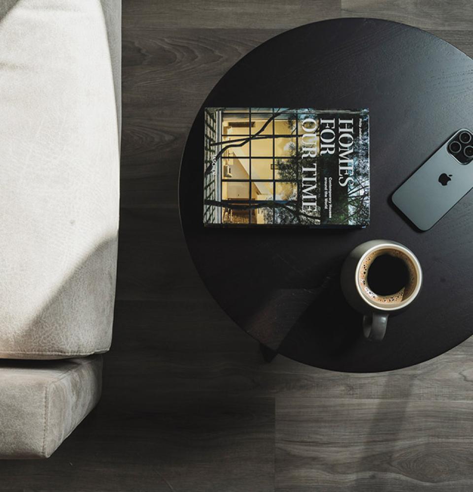 Table avec livre, smartphone et café à côté d'un canapé.