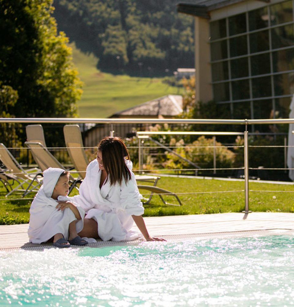 Madre e figlio in accappatoi bianchi vicino alla piscina.