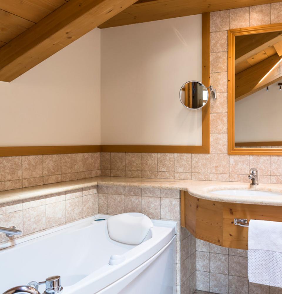 Bagno con vasca, doppio lavabo, specchio grande e dettagli in legno.