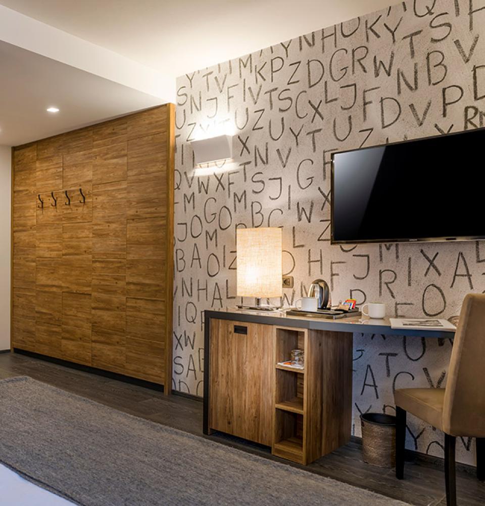 Chambre moderne avec mur décoré, TV et bureau.