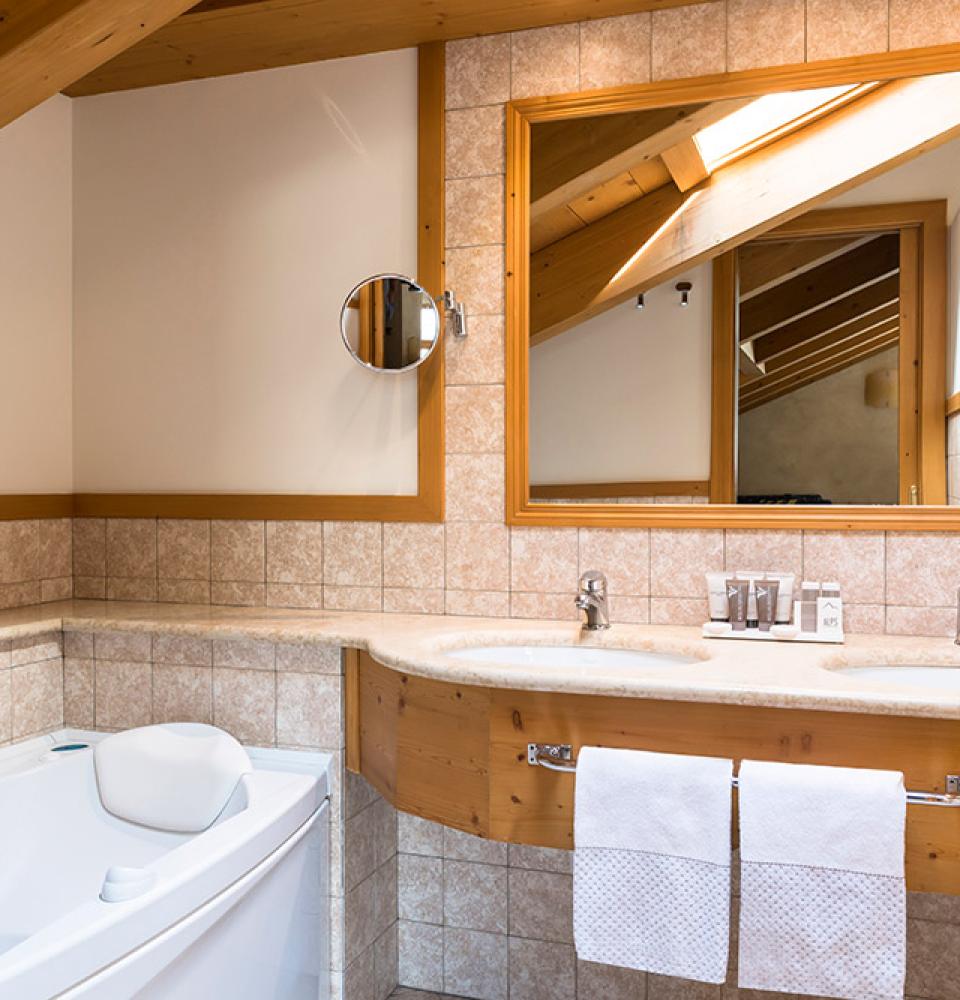 Salle de bain accueillante avec baignoire, double lavabo et grand miroir.