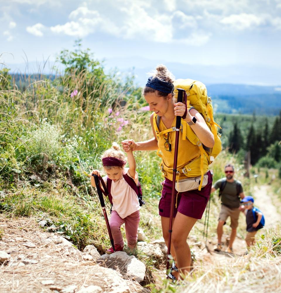 Famiglia in escursione su un sentiero di montagna, con attrezzatura da trekking.