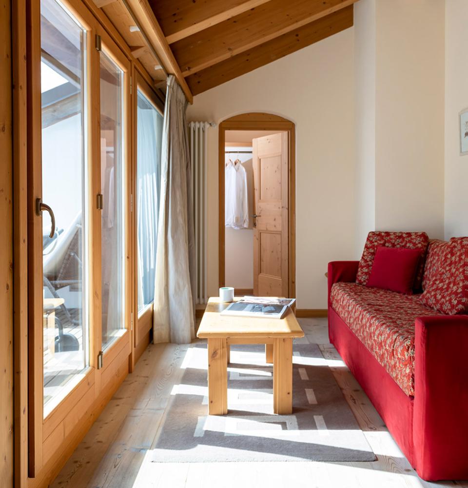 Salon lumineux avec canapé rouge et table en bois.