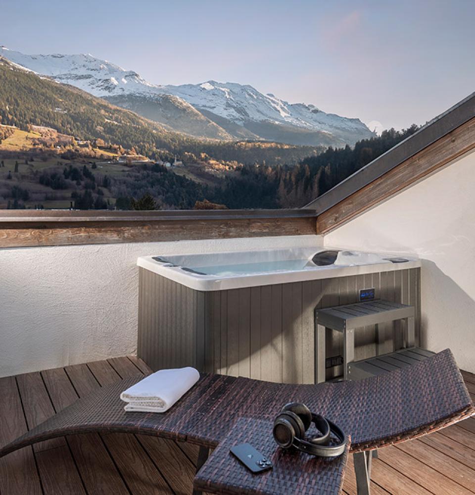 Terrasse avec jacuzzi et vue sur les montagnes enneigées.