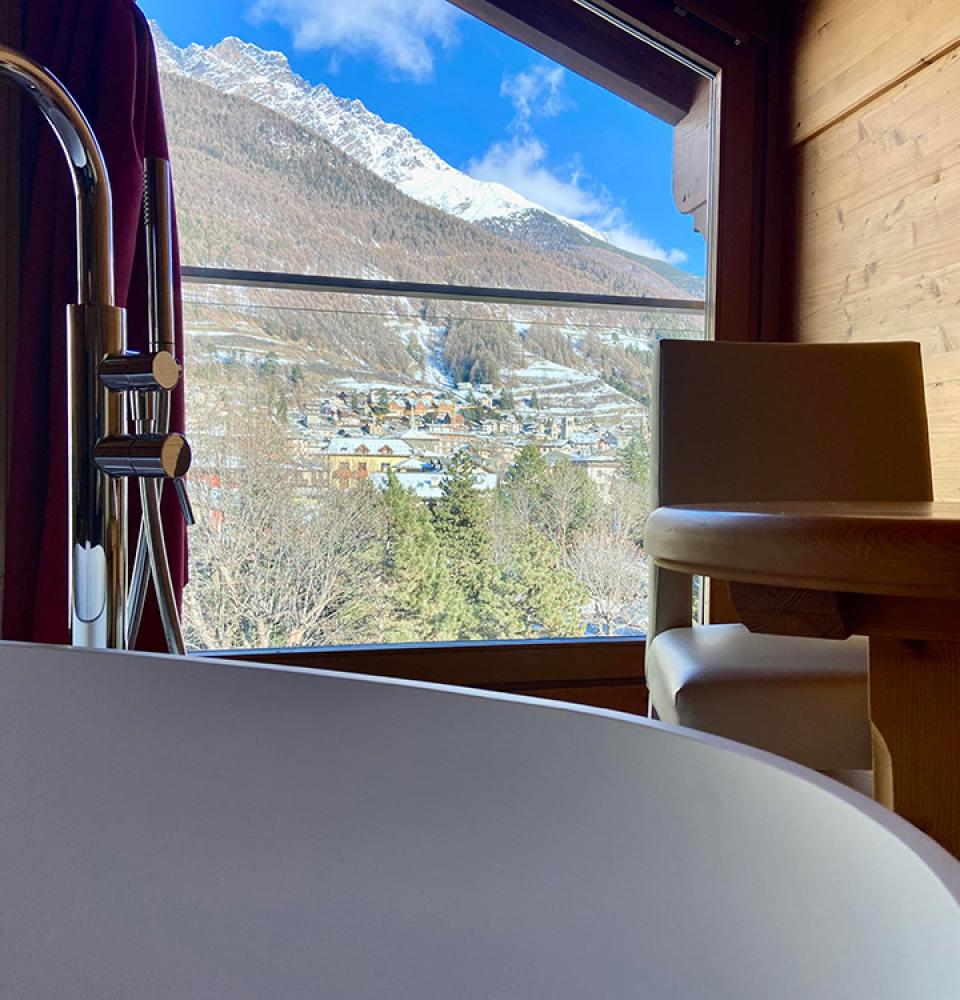 Vue montagne depuis une baignoire avec table en bois.