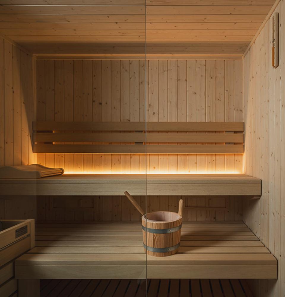 Sauna moderne en bois avec éclairage doux et seau.